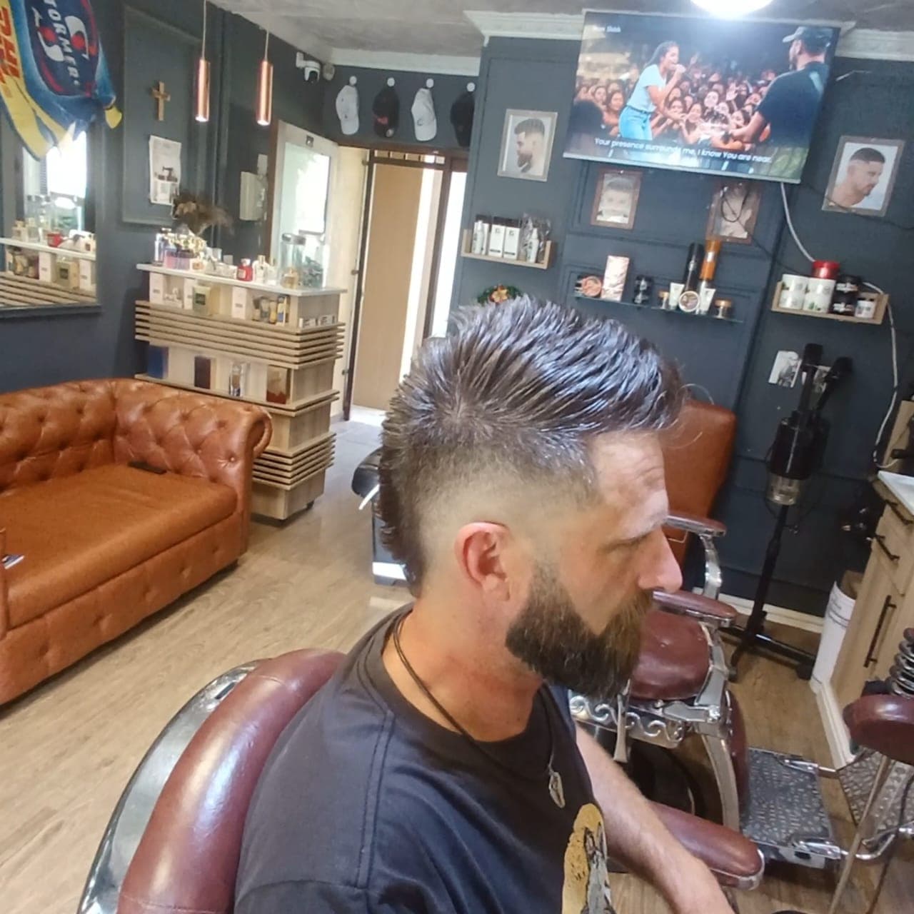 Man with a spiky textured mohawk fade and full beard in a barbershop chair.