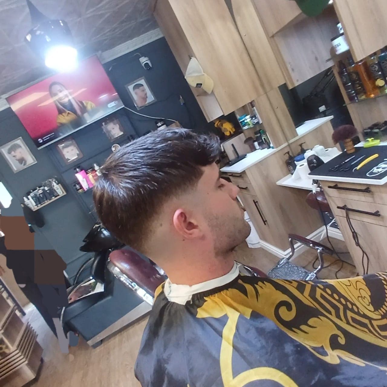 Side profile of a man with a fresh skin fade haircut in a modern barbershop.